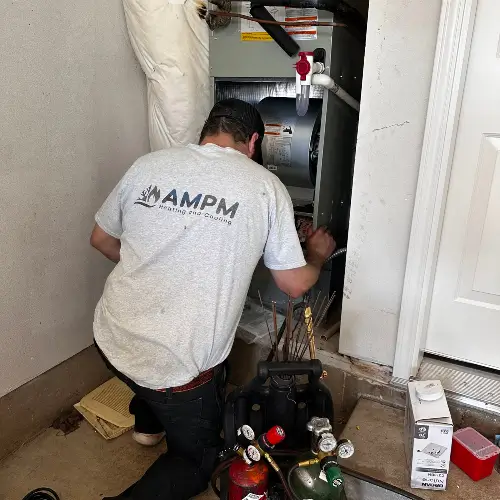 AMPM Heating and Cooling service technician doing maintenance on the furnace of a residential home in Hidden Springs